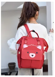 Detailaufnahme des roten Wickelrucksacks mit süßem Bärengesicht und großem Fassungsvermögen.