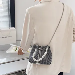Rhinestone bucket bag detail view, featuring pearl handle and silver chain strap for women.
