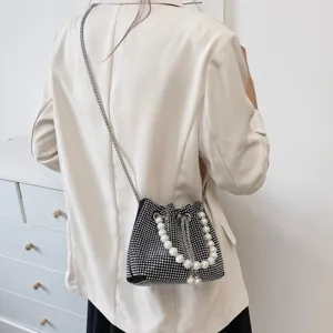 Detail shot of a black rhinestone bucket bag with pearl handle and chain strap for women.