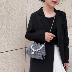 Detail shot of sparkling rhinestone bucket bag with pearl handle and metal chain strap for women.