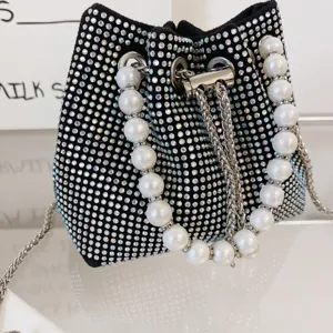 Rhinestone bucket bag detail, sparkling crystals, elegant faux pearl handle and metal chain.