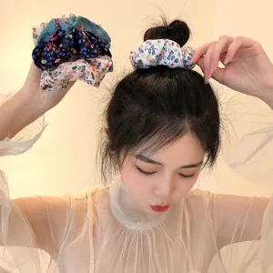 Vue détaillée d'élégants élastiques à cheveux fleuris sur un chignon en tissu doux.