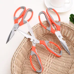 Close-up detail of multi-functional kitchen scissors featuring orange handles and sharp blades.