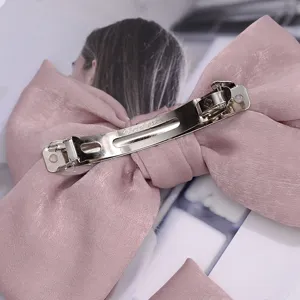 Detalle de pinza para el pelo con lazo de saten rosa y barrita metalica muy suave.