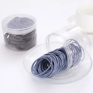 Detailed close-up view of boxed grey elastic hair ties, neatly packed in transparent plastic jars.