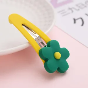 Vue de détail de la jolie pince à cheveux fleur jaune et verte, montrant un design en résine.