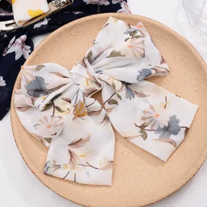Detail shot of a sweet floral chiffon hair bow clip, elegant spring hair accessory for women.