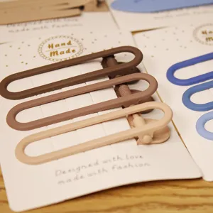 Close-up detail of minimalist hair clips on display card, matte finish design, fashion style.