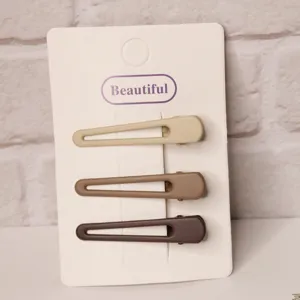 Detailed view of three minimalist matte hair clips in milk tea colors on a display card.