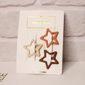 Close-up view of three milk tea colored hollow star hair clips on white card display.