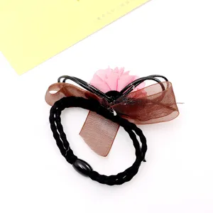Detail shot of a cute hair tie featuring a brown organza bow and pink flower design.