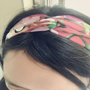 Gedetailleerde close-up van de roze bloemige satijnen haarband met twist, zachte stof en patroon.