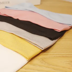 Vue détaillée de bandeau de sport côtelé coloré empilé soigneusement sur table en bois.