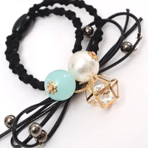 Close-up detail of a stylish black hair tie decorated with white pearl and gold geometric charm.