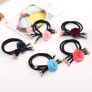 Close-up detail of stylish floral hair ties with fabric camellia flowers and metal beads.