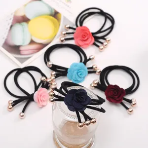 Closeup of stylish black hair ties with fabric camellia flowers and metal bead ends. Detail.