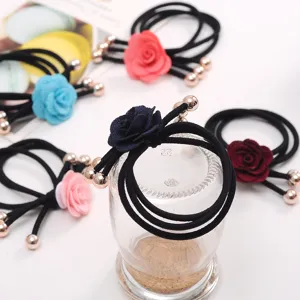 Detailed view of floral hair ties featuring fabric roses, elastic ropes and metal bead ends.