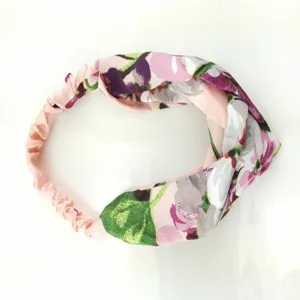 Detail van de zijden haarband met bloemenprint, stijlvolle gedraaide knoop en elastische band.