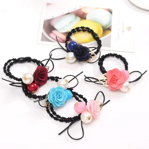 Close-up of colorful fabric flower hair ties with pearls and golden leaf charms detail shot.