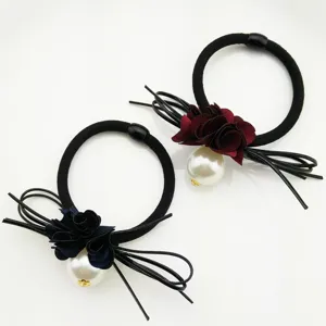 Close-up detail of elegant floral hair tie featuring large pearl and fabric flower accents.