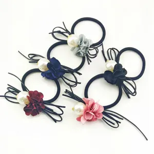 Detailed view of fashionable fabric camellia hair ties with large pearls and elastic bands.