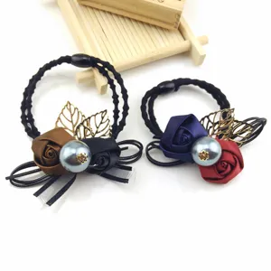 Detail shot of elegant rose hair ties featuring large pearls, satin flowers and metal leaves.