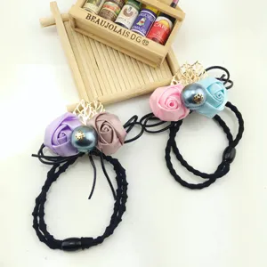 Detail shot of fabric rose hair ties with big pearl and gold leaf, elastic black rope.