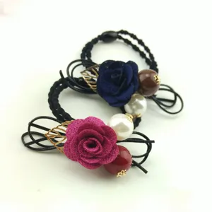 Close up detail of elegant black hair tie featuring a blue and pink fabric rose and pearl.