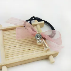 Delicate hair tie with pink organza bow, sparkling rhinestone and cute pearl pendant details.