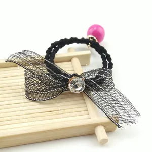 Detail shot of black mesh bow hair tie with sparkling rhinestone and pink pearl pendant.