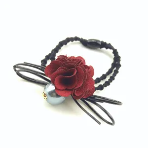 Red fabric flower and grey pearl hair tie detail, elegant black cord hair accessory.