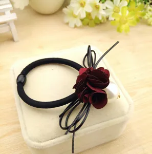 Detail view of a black hair tie featuring a dark red fabric flower and a large pearl.