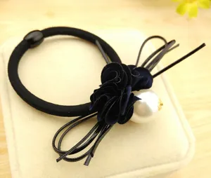 Detailed view of the elegant black hair tie featuring a dark blue camellia flower and pearl.
