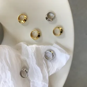 Detailaufnahme breiter gewölbter Silber- und Goldringe im minimalistischen Design.