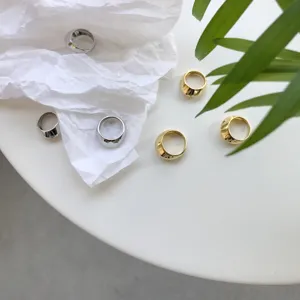 Detailansicht minimalistischer geschwungener Ringe in Gold und Silber mit glatter Metalloberfläche.