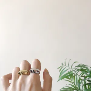 Nahaufnahme zweifarbiger geschwungener Ringe an Hand mit Pflanzenhintergrund elegant.