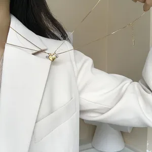 Nahaufnahme einer filigranen goldenen Magnet-Herz-Anhänger-Halskette mit süßen Flügeln.
