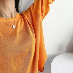 Nahaufnahme Detail der Münzanhänger Halskette getragen mit einem hellen orangefarbenen Top.