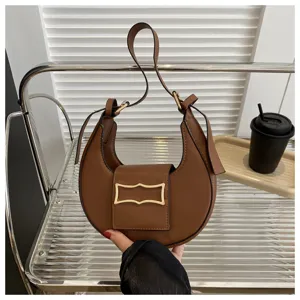Detailed view of the brown crescent hobo shoulder bag featuring stylish metal buckle hardware.