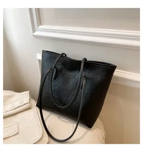 Close up of black embossed tote bag showing detailed texture, brand logo and cute patterns.