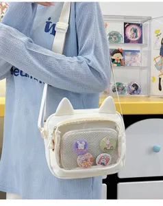 Detailed shot of a cute white canvas ita bag with cat ears, clear front pocket and pins.