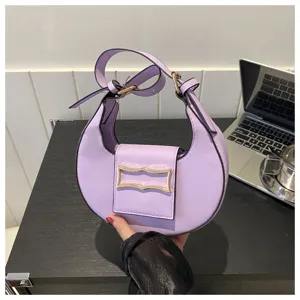 Detail shot of the stylish purple crescent shoulder bag featuring metal buckle and handle.