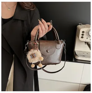 Stylish retro brown leather handbag for women, versatile crossbody shoulder bag with cute plush charm.