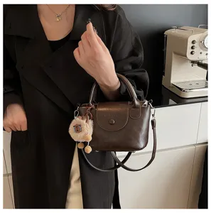 Retro brown leather handbag for women, chic small crossbody shoulder tote with cute plush charm.