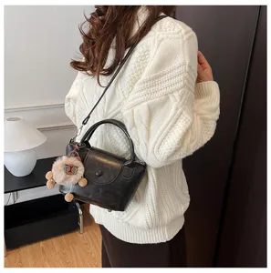 Stylish black leather top handle bag with cute plush charm for women daily fashion wear.