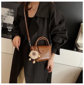Vintage brown leather women handbag detail showing texture, top handle, and cute plush charm.