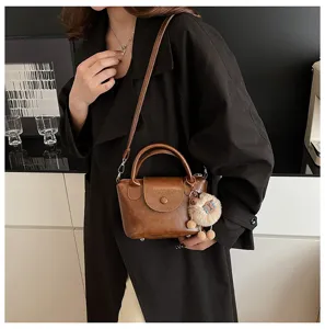 Vintage brown top handle shoulder bag for women, retro crossbody bag with cute plush charm.