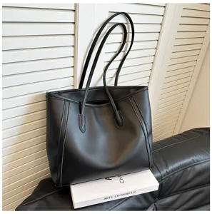 Detailed view of the black leather tote bag featuring dual shoulder straps and spacious capacity.