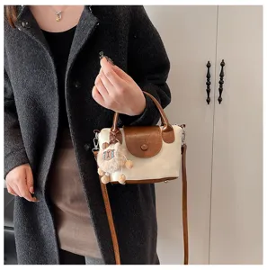 Close-up detail of stylish women handbag with brown flap and cute plush charm pendant.