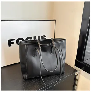 Detailed view of black faux leather tote bag, minimalist commuter design with double straps.